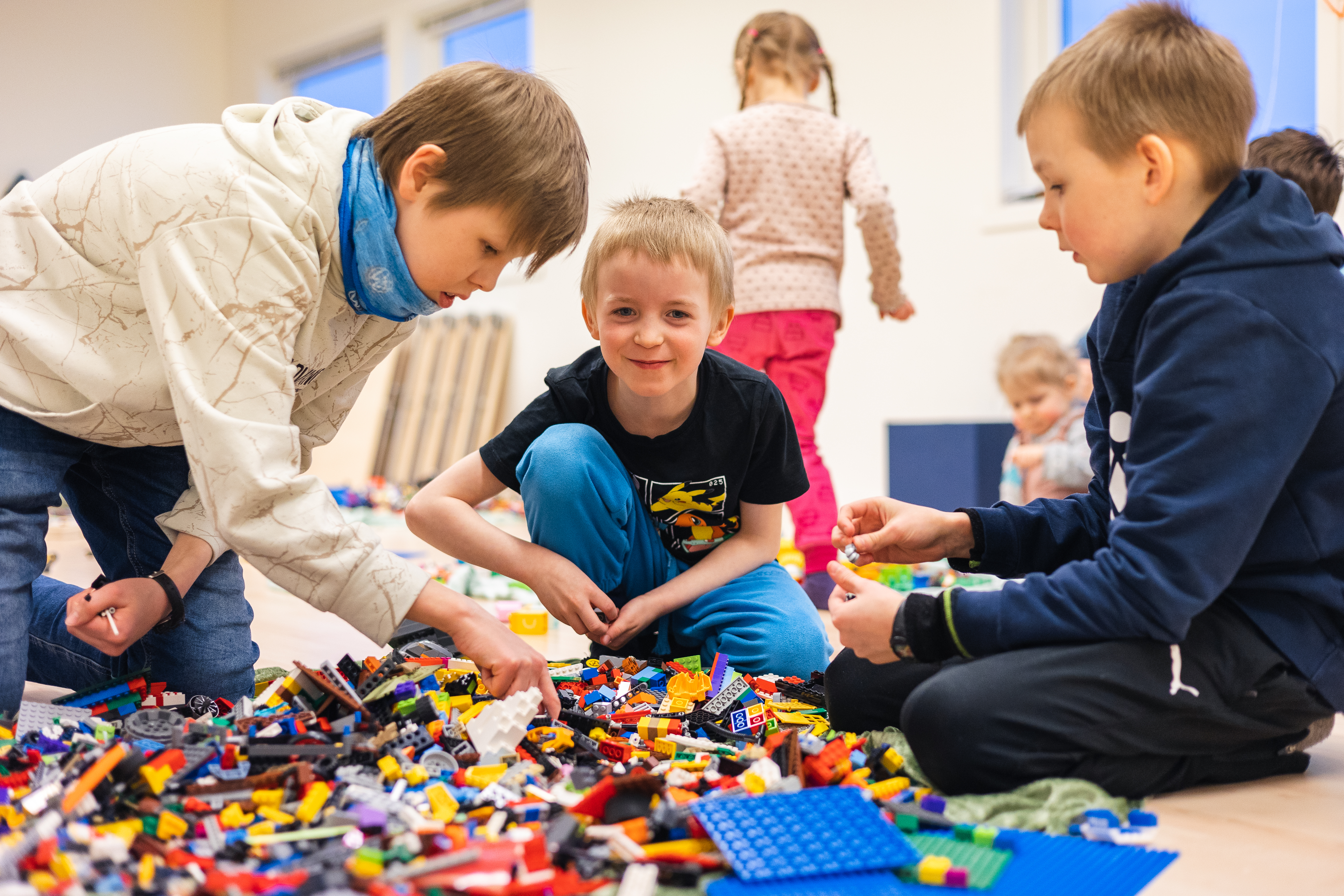 Tre barn som leker med lego.